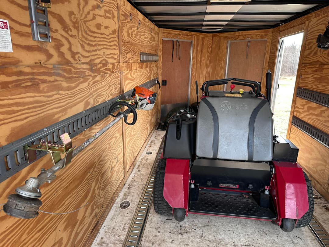Interior of a trailer with a lawn mower and gardening tools neatly stored.