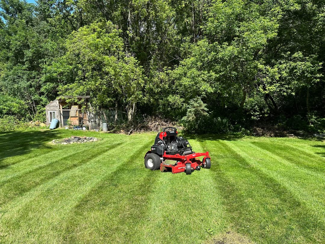 Lawn mower on a well-maintained grassy area with trees in the background.